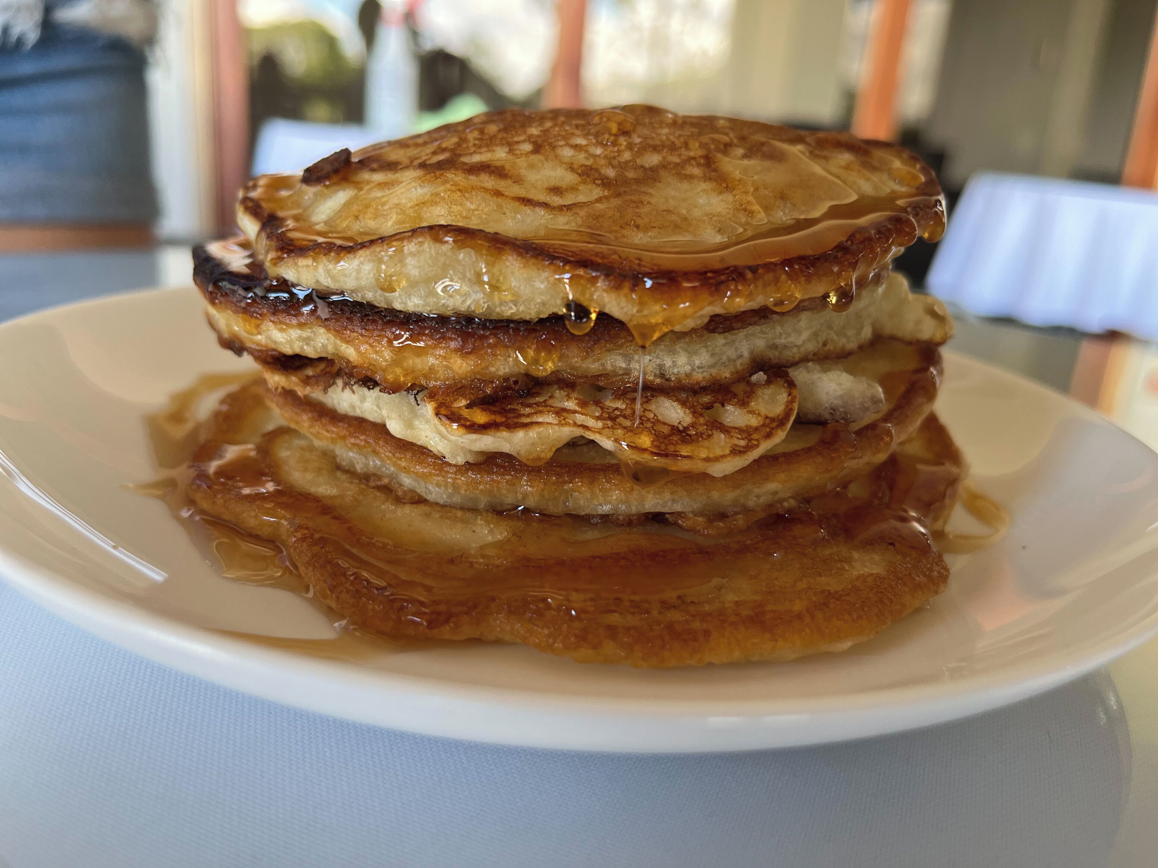 A stack of pancakes with syrup on a white plate.