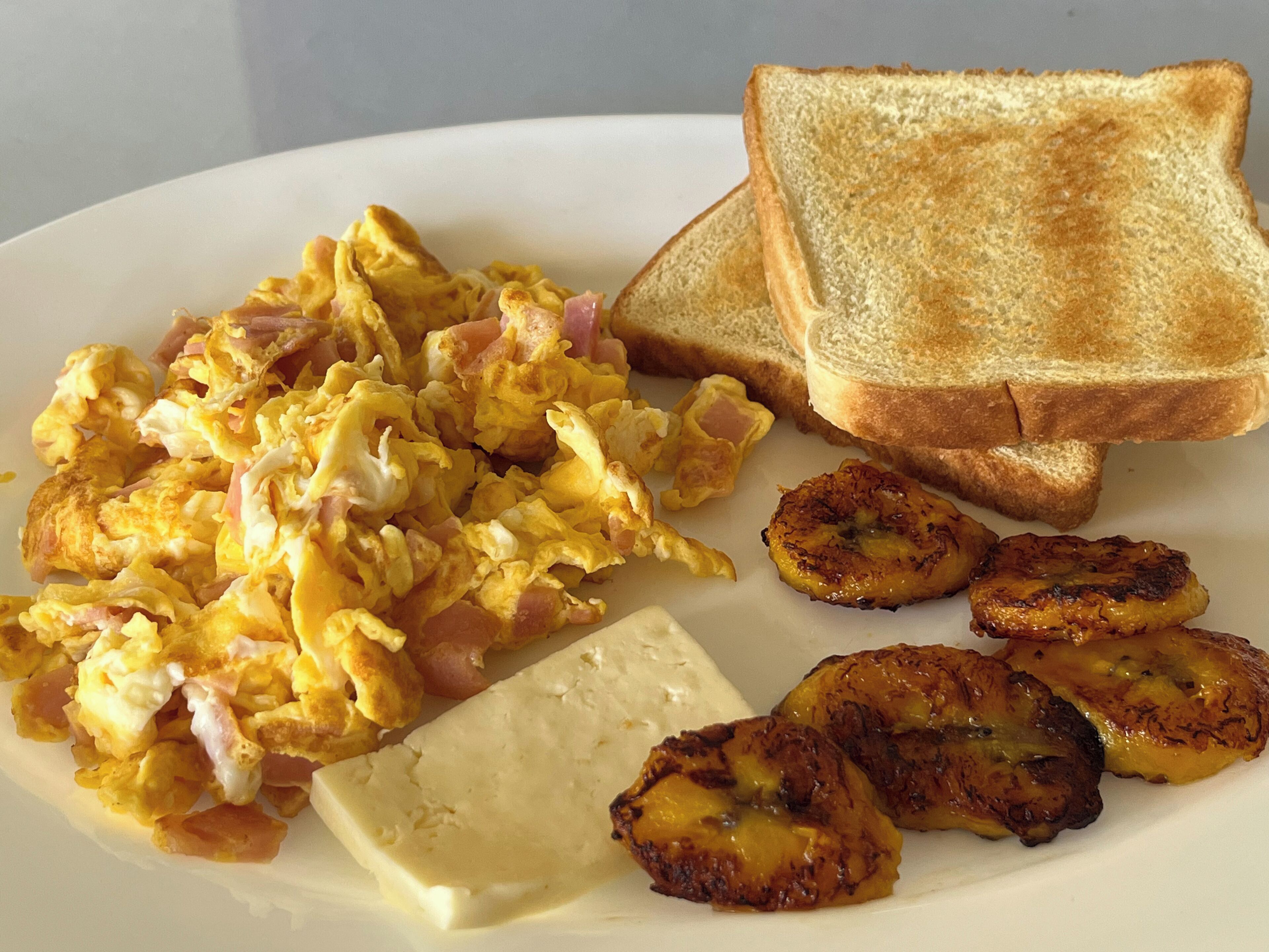 Scrambled eggs, toast, and grilled bananas on a plate.