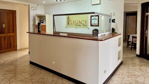 A reception desk with a 'Legacy Boutique Hotel' sign, a wooden door, and a tiled floor. - Legacy Boutique Hotel (Quesada)