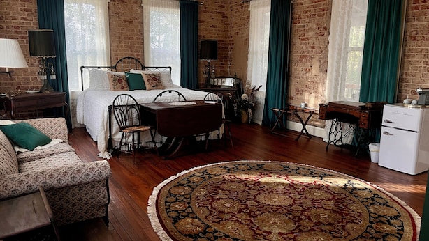 A room with a bed, a dining table, a small desk, and a vintage refrigerator. - Tanglewood Inn (Greenville)