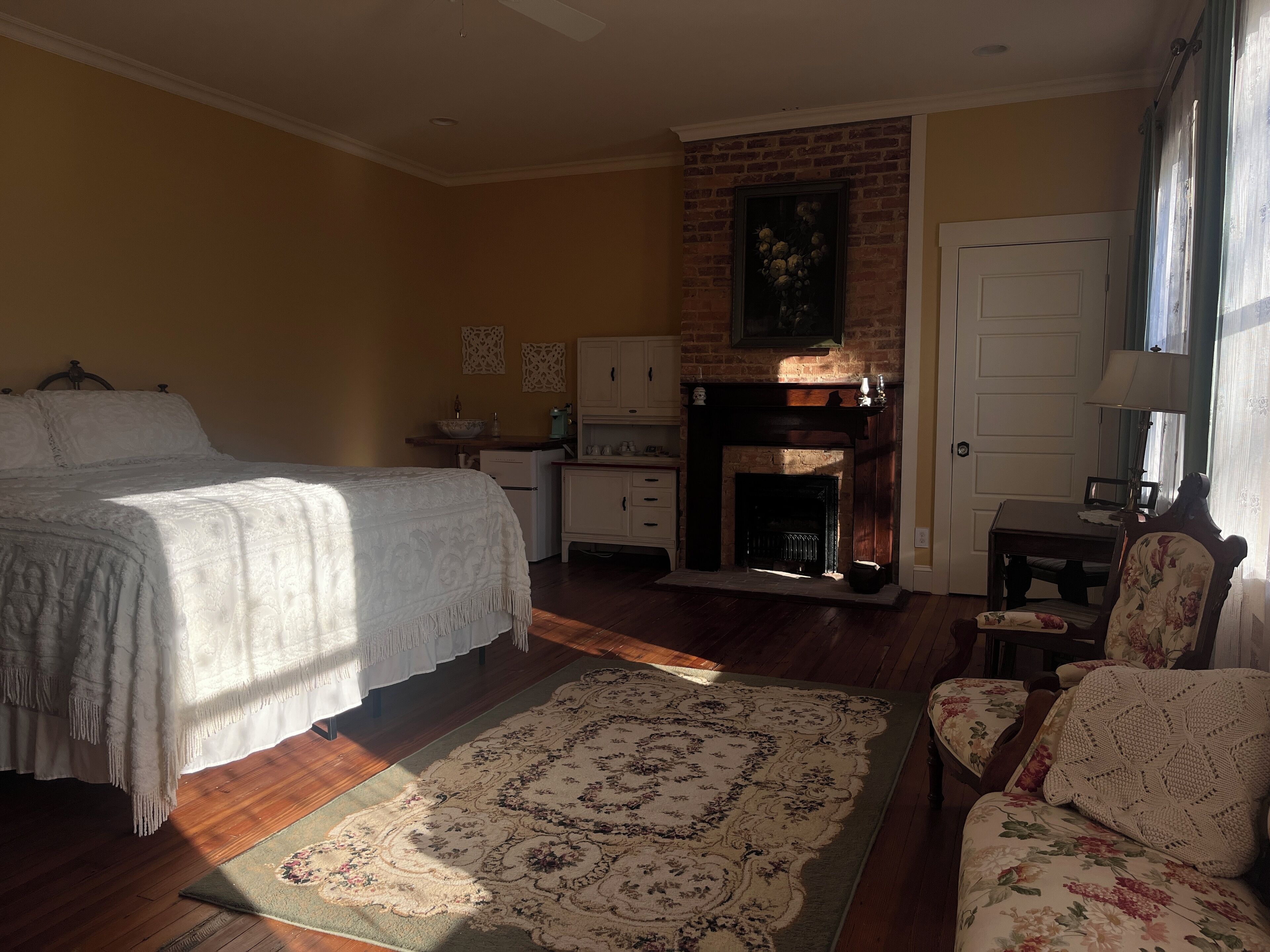 Une chambre à coucher avec un lit, une cheminée, une petite table et une chaise.