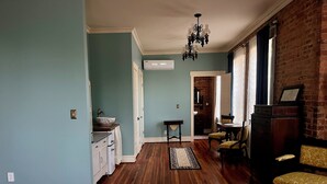 A spacious living area with hardwood flooring, a chandelier, and a dining area with yellow upholstered chairs. - Tanglewood Inn (Greenville)