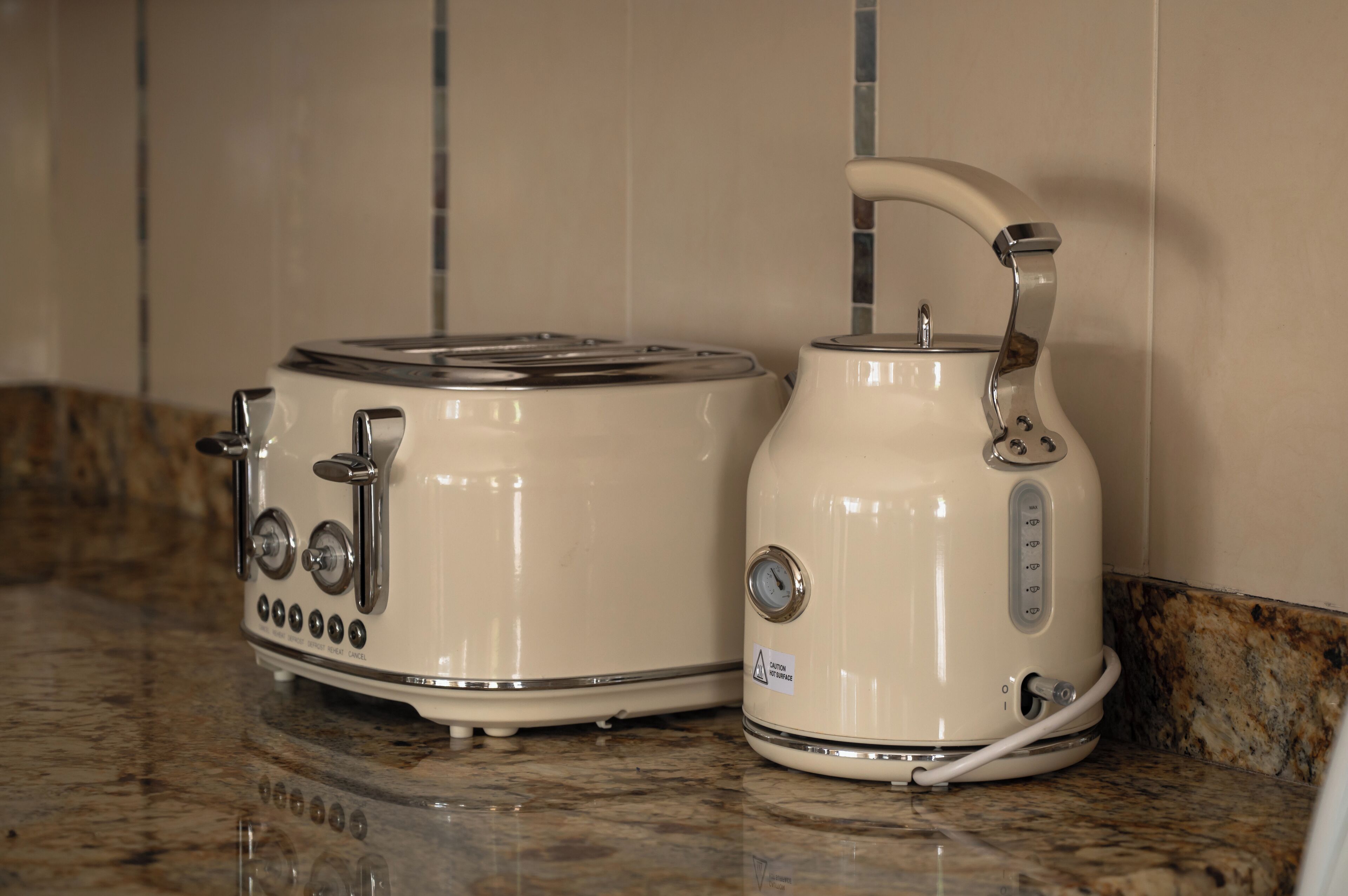 Zwei weiße Küchengeräte, ein Toaster und ein Wasserkocher, auf einer Arbeitsplatte aus Granit.