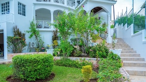 A white building with a garden, steps, and a fence. - Awaii Jamaica (Montego Bay)