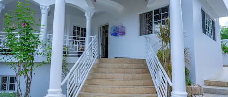 A staircase with white railings leading to a covered entrance with columns.