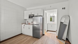 Una cocina moderna con armarios blancos, electrodomésticos de acero inoxidable y suelo de madera.