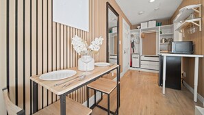 Eine moderne Küche mit Holzvertäfelung, einem Esstisch mit weißen Tellern und einer Mikrowelle auf einer Arbeitsplatte.