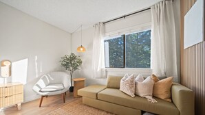 Ein modernes Wohnzimmer mit Sofa, Sessel und einem kleinen Beistelltisch.