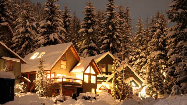 A lodge with multiple cabins surrounded by snow-covered trees.