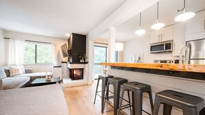 A modern kitchen with a central island, bar stools, and a fireplace.