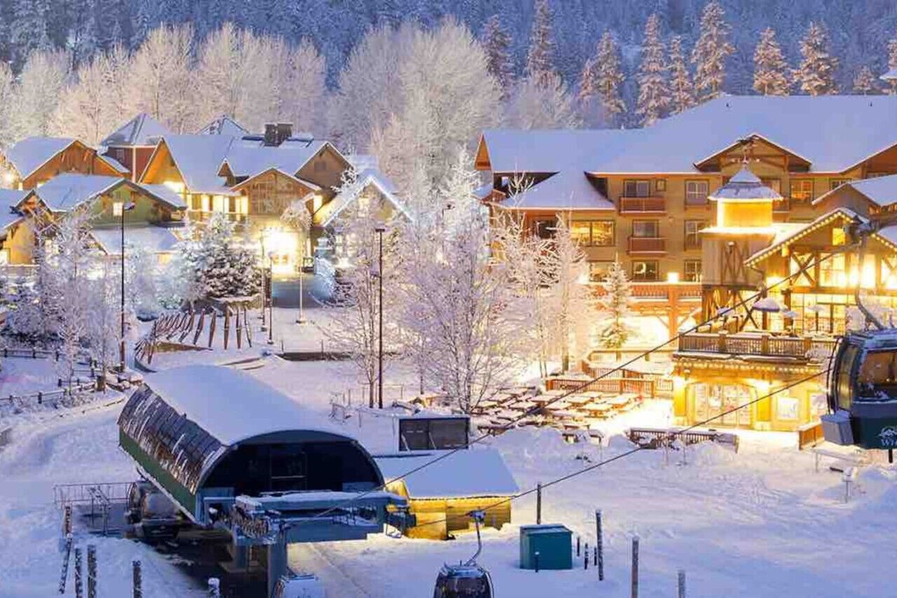 Ein mit Schnee bedecktes Chalet mit mehreren Gebäuden und einer Seilbahn.