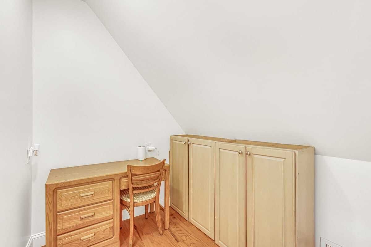 Una habitación pequeña con un escritorio de madera, una silla y un armario.