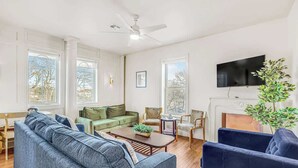 Ein Wohnzimmer mit Sofa, Sesseln, Couchtisch, Kamin und Fernseher.