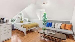 Ein Schlafzimmer im Loft-Stil mit Bett, Sofa, Couchtisch und Schreibtisch.