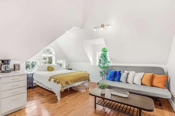 Un dormitorio estilo loft con cama, sofá, mesa de centro y escritorio.