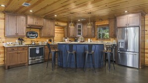 Une cuisine moderne avec un lambris en bois, des appareils électroménagers en acier inoxydable et des tabourets de bar.