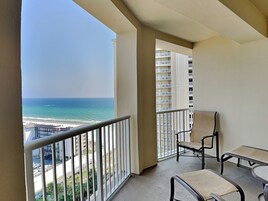 Ein Balkon mit Blick auf das Meer und die Stadt. Ein Tisch und zwei Stühle sind vorhanden.