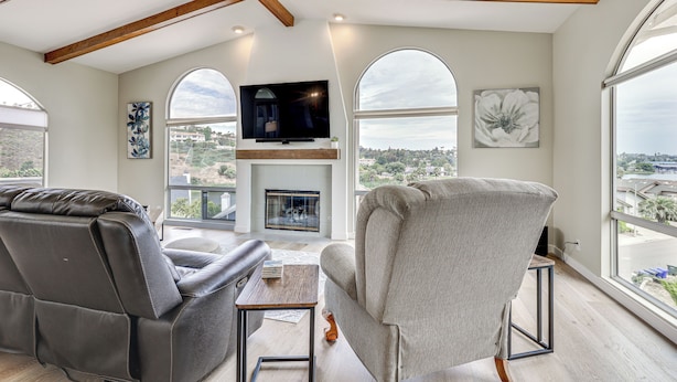 A modern living room with a fireplace, a television, and large windows offering a city view. - San Marcos Getaway w/ Deck & Lake Views! (San Marcos)