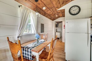 Un coin repas avec une table en bois, des chaises et une horloge au mur.