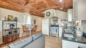 Una cocina acogedora con vigas de madera en el techo, una zona de comedor con sofá y sillas, y una kitchenette con electrodomésticos modernos.