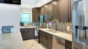 A modern kitchen with dark wooden cabinets, a stainless steel refrigerator, and a marble countertop. - Charming Bear Lake Cottage w/ Dock & Paddleboards! (Bear Lake)