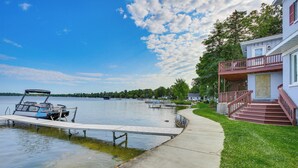 A waterfront property with a dock, a house with a balcony, and a clear view of the lake. - Charming Bear Lake Cottage w/ Dock & Paddleboards! (Bear Lake)