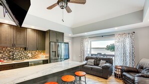 A modern kitchen with a large island, bar stools, and a view to the outside. - Charming Bear Lake Cottage w/ Dock & Paddleboards! (Bear Lake)