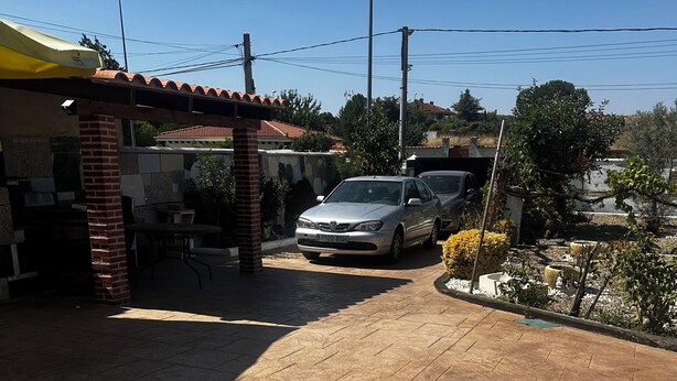 Une allée pavée mène à un bâtiment doté d’un toit en tuiles et d’un pilier en briques.