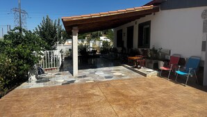 Un patio couvert doté d’un sol carrelé, de meubles d’extérieur et d’un bâtiment blanc avec un toit en tuiles.