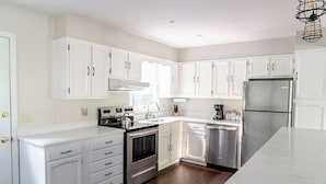 Una cocina moderna con armarios blancos, electrodomésticos de acero inoxidable y encimera de mármol.
