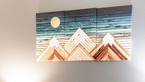 Una cama con una cubierta blanca y esponjosa, una mesita de noche con una lámpara y una pared con un cuadro de un paisaje a la luz de la luna.