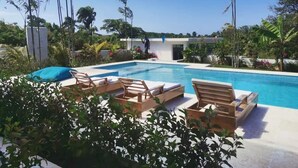 Una piscina con sillas de descanso y un edificio moderno al fondo.