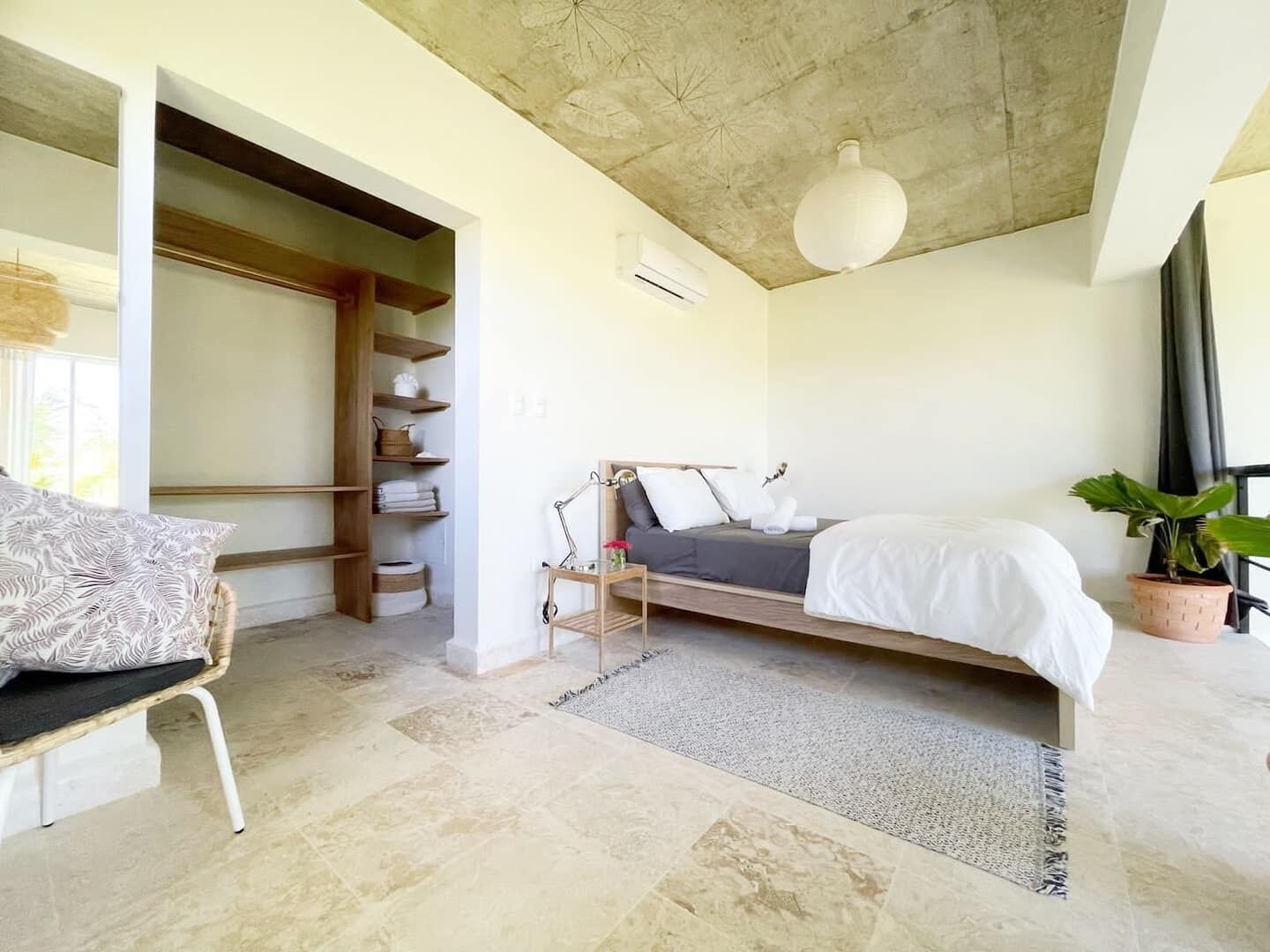Ein Schlafzimmer mit Bett, Nachttisch, Stuhl, Kleiderschrank und Deckenventilator.