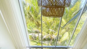 Una sala moderna con un gran ventanal que da a un jardín tropical.