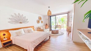 A bedroom with a bed, bedside table, and a view of the outdoors. - Casa Amour, cosy studio en bord de mer (Orient Bay)