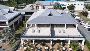 A hotel with a rooftop terrace, outdoor seating area, and a parking lot. - Marina Beach – 2 Adjacent Apartments, Marina View, Walkable Beach (Anse Marcel)