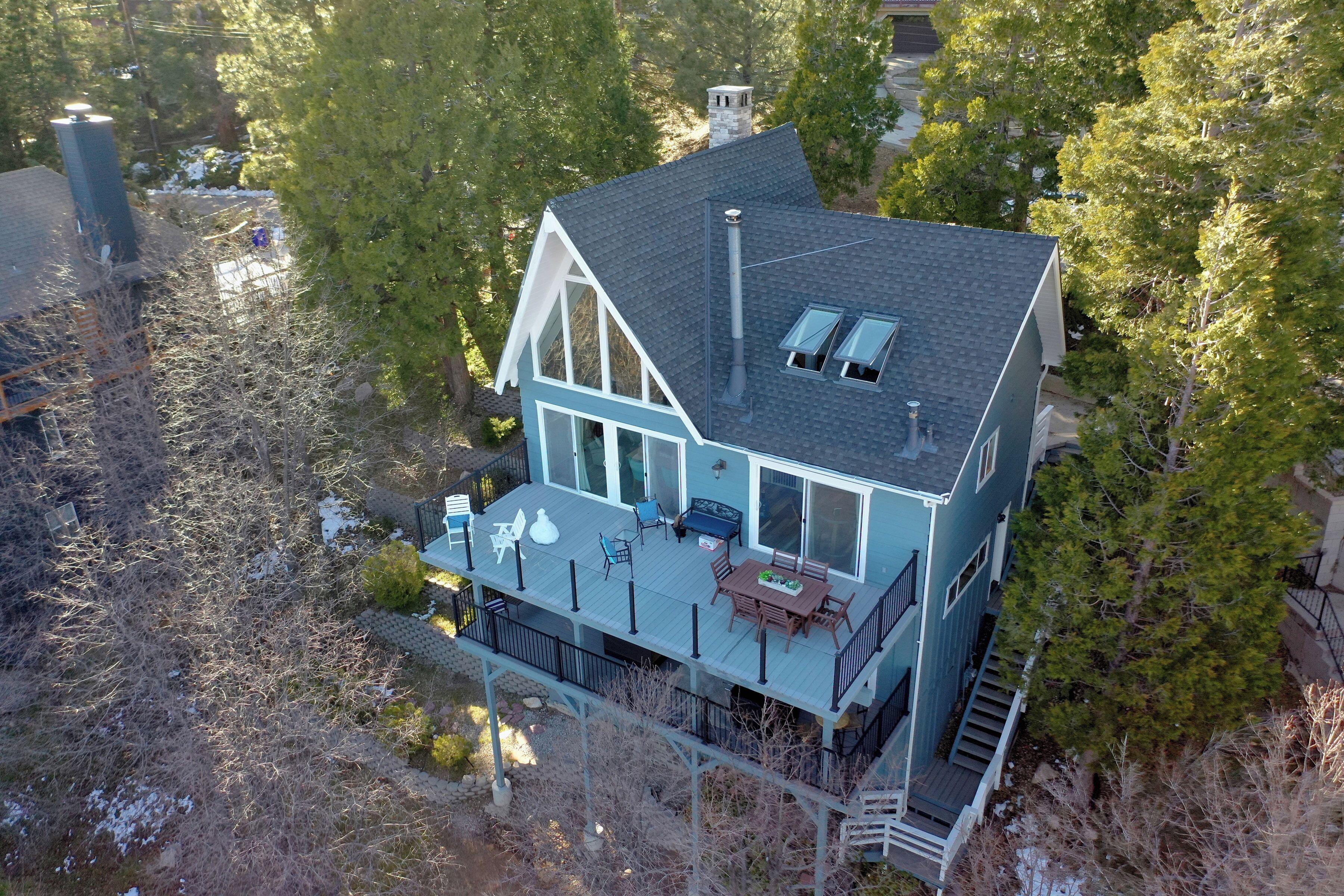 A two-story house with a deck, large windows, and a chimney.