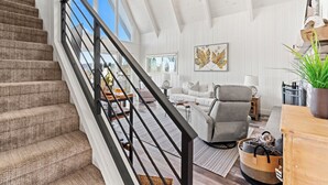 En rummelig opholdsstue med trappe, sofa, stol og spisebord.