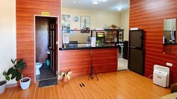 Eine Hotte lobby mit Holzboden, einer Rezeption, einer kleinen Küchenzeile und einem Spiegel an der Wand.