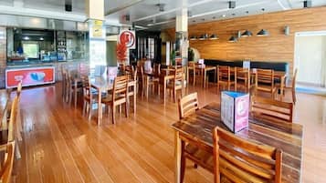 A restaurant with wooden flooring, tables, and chairs.