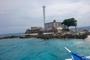 A lighthouse on a rocky outcrop with clear blue water. - RedDoorz @ 4ks Pension House Bogo City Cebu (Bogo City)
