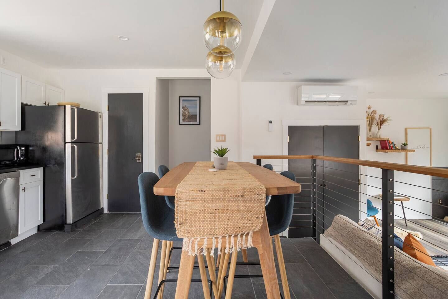A modern kitchen with stainless steel appliances, a wooden dining table, and a staircase leading to a loft area.