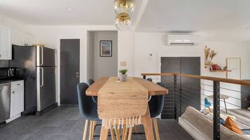 A modern kitchen with stainless steel appliances, a wooden dining table, and a staircase leading to a loft area.