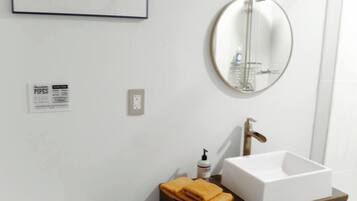 Een badkamer met een wit toilet, een wastafel met een blauwe kast, een spiegel en een lijst met een foto aan de muur.