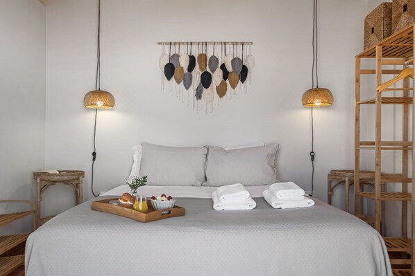 A neatly arranged bedroom with a bed, bedside tables, a wall-mounted light fixture, and a wooden ladder.