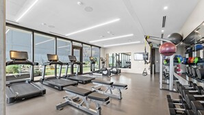 A modern gym with treadmills, weight machines, and exercise balls. - Rainey St 1BR | Heated Pool | Gym | Bar | DT ATX (Austin)