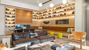 A modern living room with a leather sofa, a coffee table, and a bookshelf filled with books. - Rainey St 1BR | Heated Pool | Gym | Bar | DT ATX (Austin)