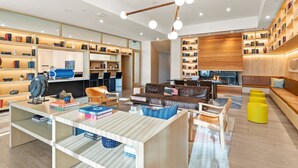 A modern library with bookshelves, a fireplace, and comfortable seating areas. - Rainey St 1BR | Heated Pool | Gym | Bar | DT ATX (Austin)