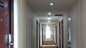 A long, narrow hotel corridor with doors on both sides, leading to individual rooms. - Hengdian Jinwo Hotel (Dongyang)