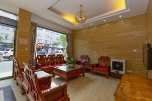 A hotel lobby with wooden furniture, a television, and a large window.